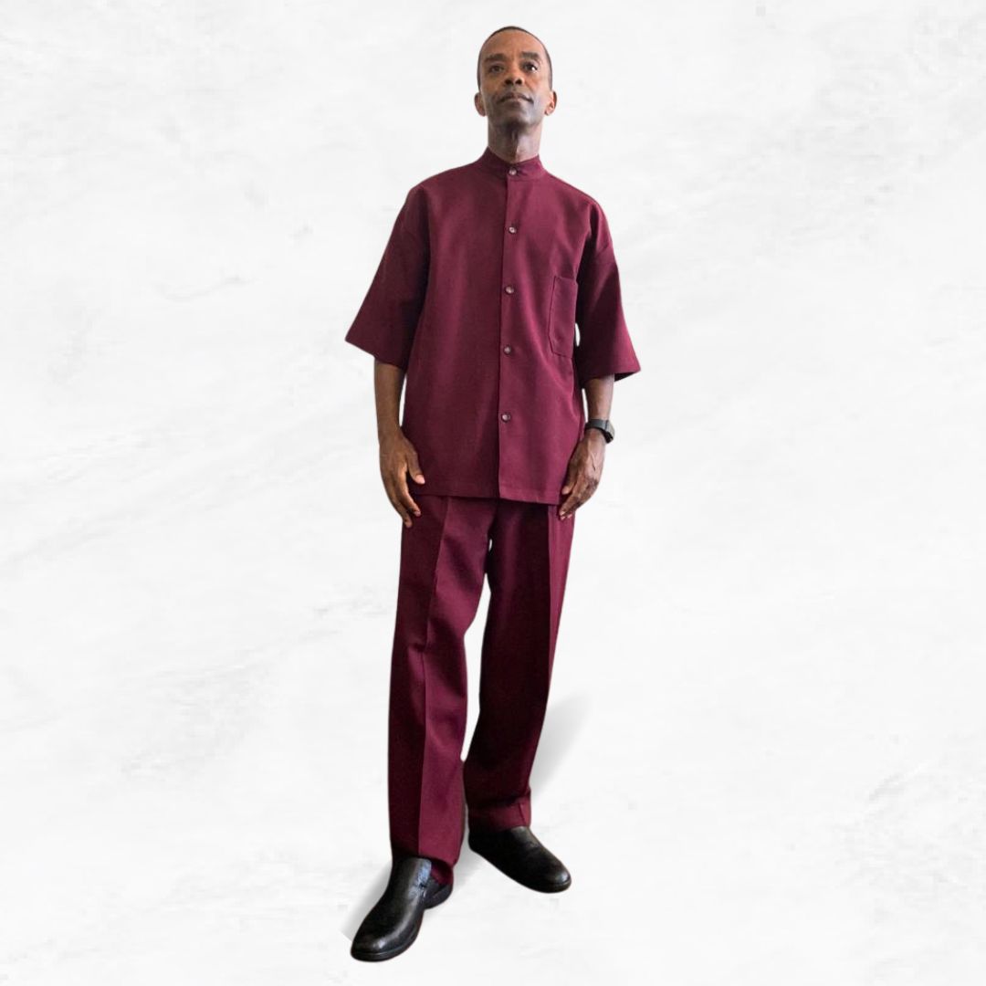 Aleem wearing a maroon modest leisure suit from Kameelah's Closet, designed for members of the Nation of Islam, captured in a striking low-angle shot.