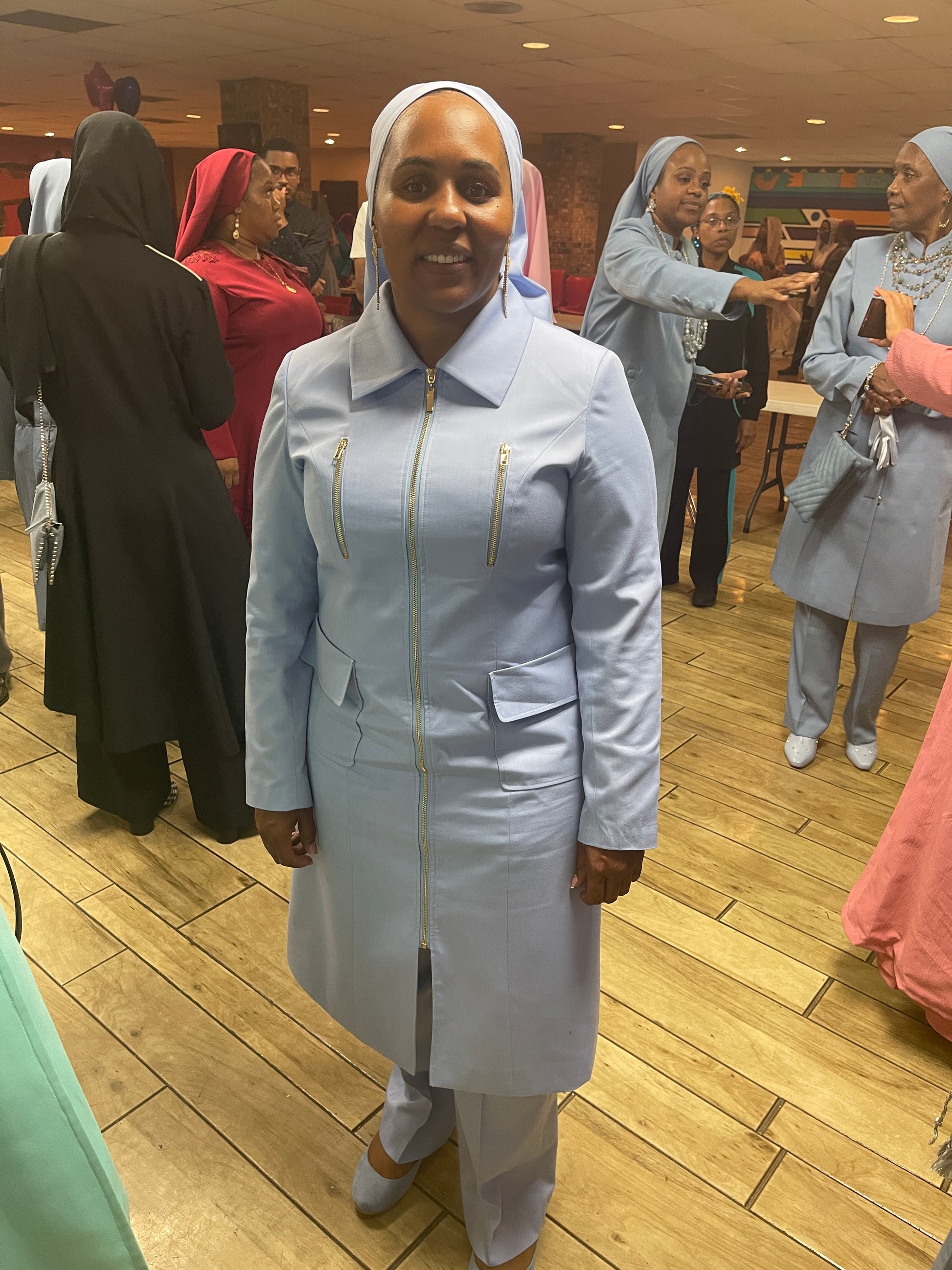 Full-body view of Vicky modeling the Rashidah three-piece light blue garment from a tilted front and side angle, designed for Muslim sisters in the Nation of Islam who value women's modest clothing.